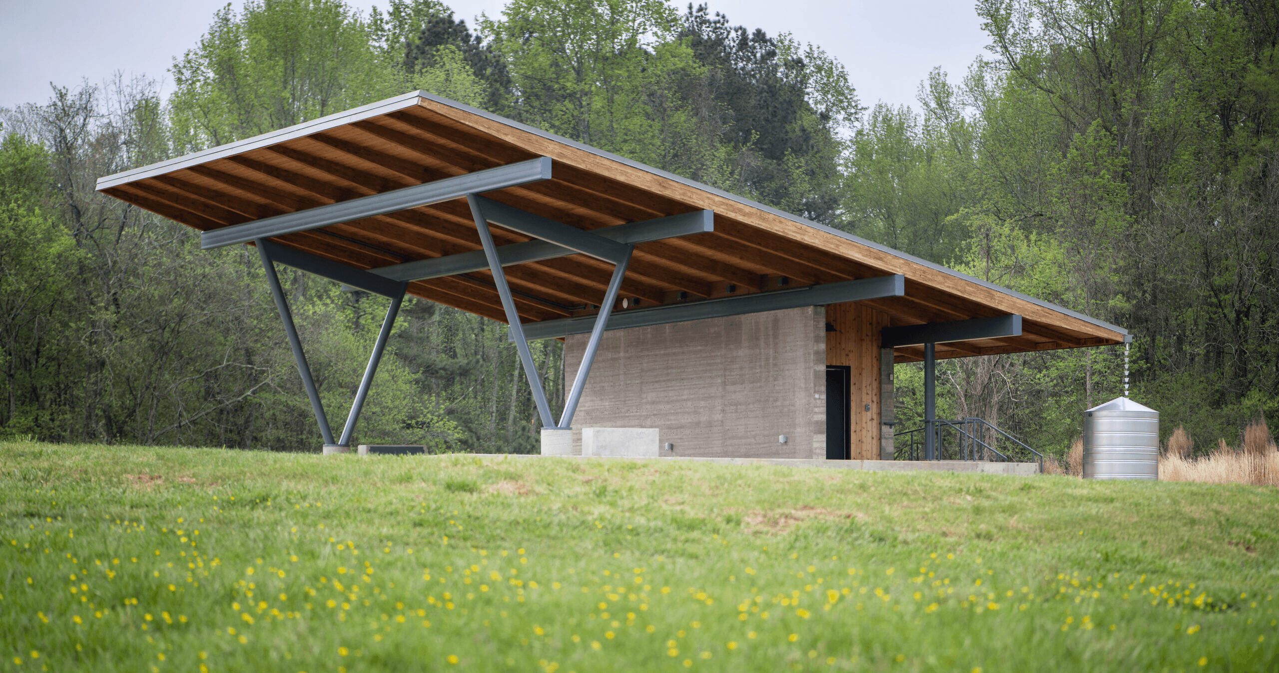 a small shelter in a grassy field with trees in the background