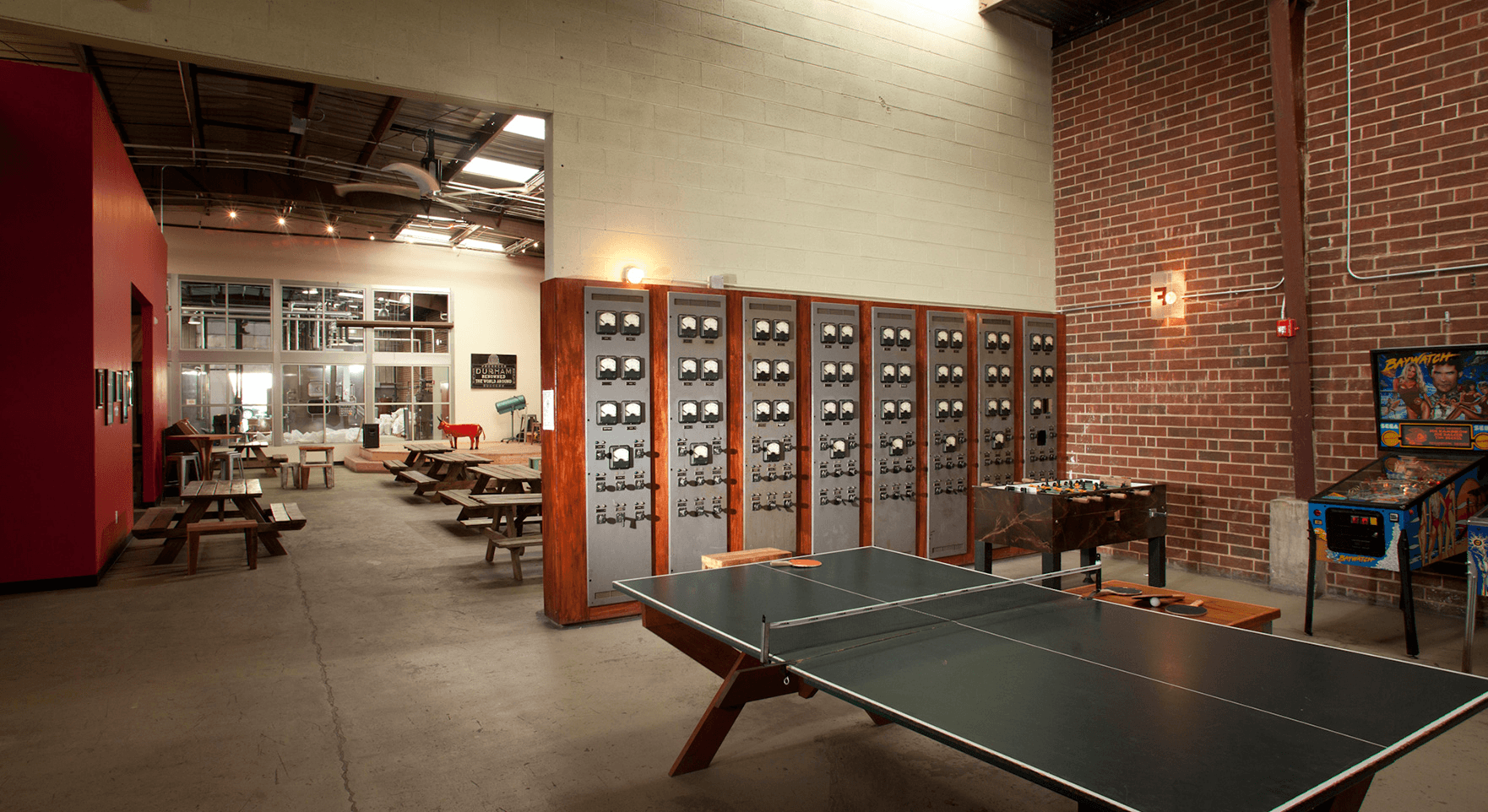 a ping pong table in a large room with a lot of tables and chairs